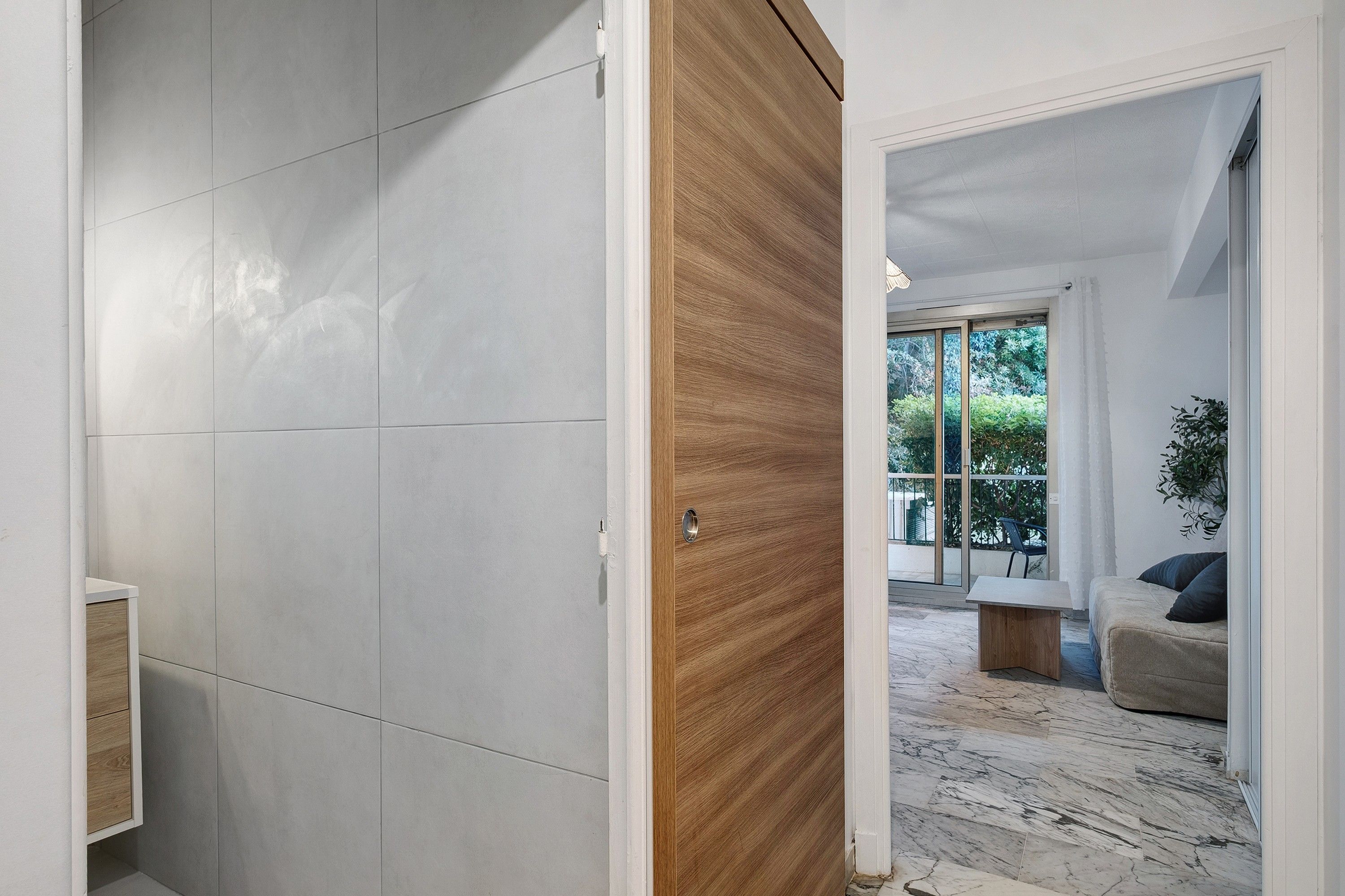 A modern interior with a wooden door leading to a living area with a sofa and a coffee table.