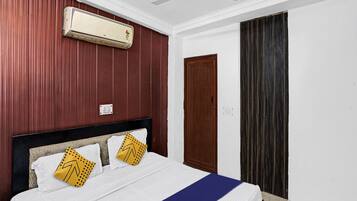 Un dormitorio con cama, aire acondicionado, ventilador de techo, puerta y ventana con cortinas.