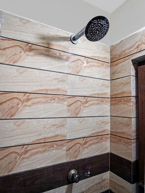 Un baño con pared de azulejos que presenta un diseño tipo mármol y un cabezal de ducha empotrado.