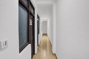 Un pasillo con paredes blancas y piso de baldosas que conduce a una puerta con la indicación 'Room 305'.