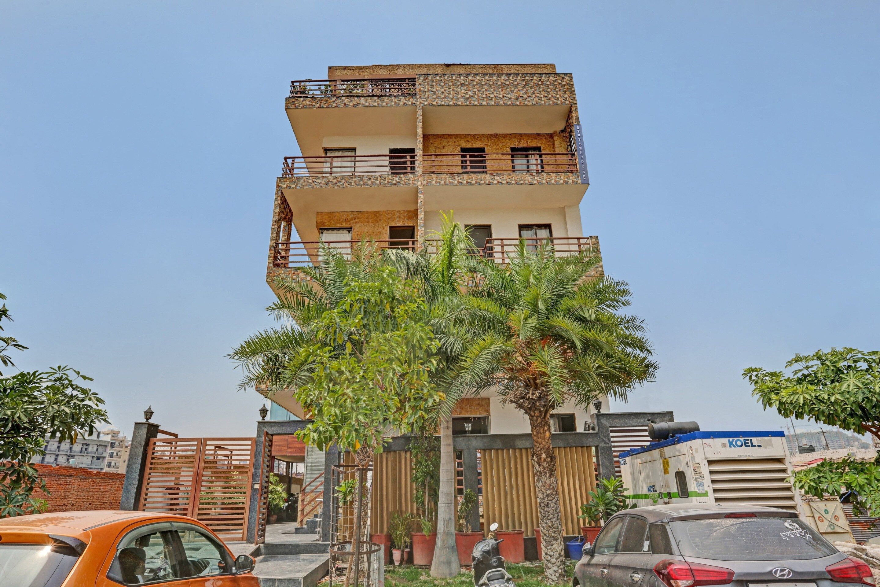 Un immeuble résidentiel à plusieurs étages, doté de balcons, d’une entrée sécurisée et d’un palmier au premier plan.