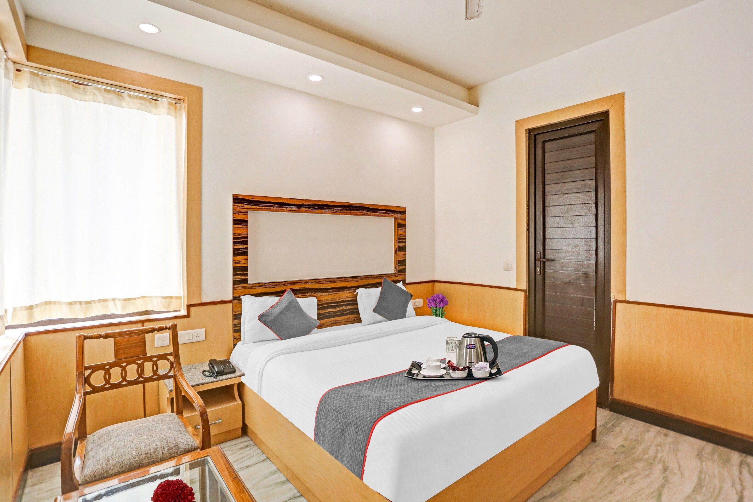 Une chambre d’hôtel avec un lit, une table de chevet, une chaise et une porte.