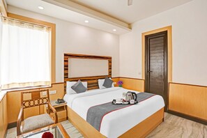 Een hotelkamer met een bed, nachtkastje, stoel en een deur.