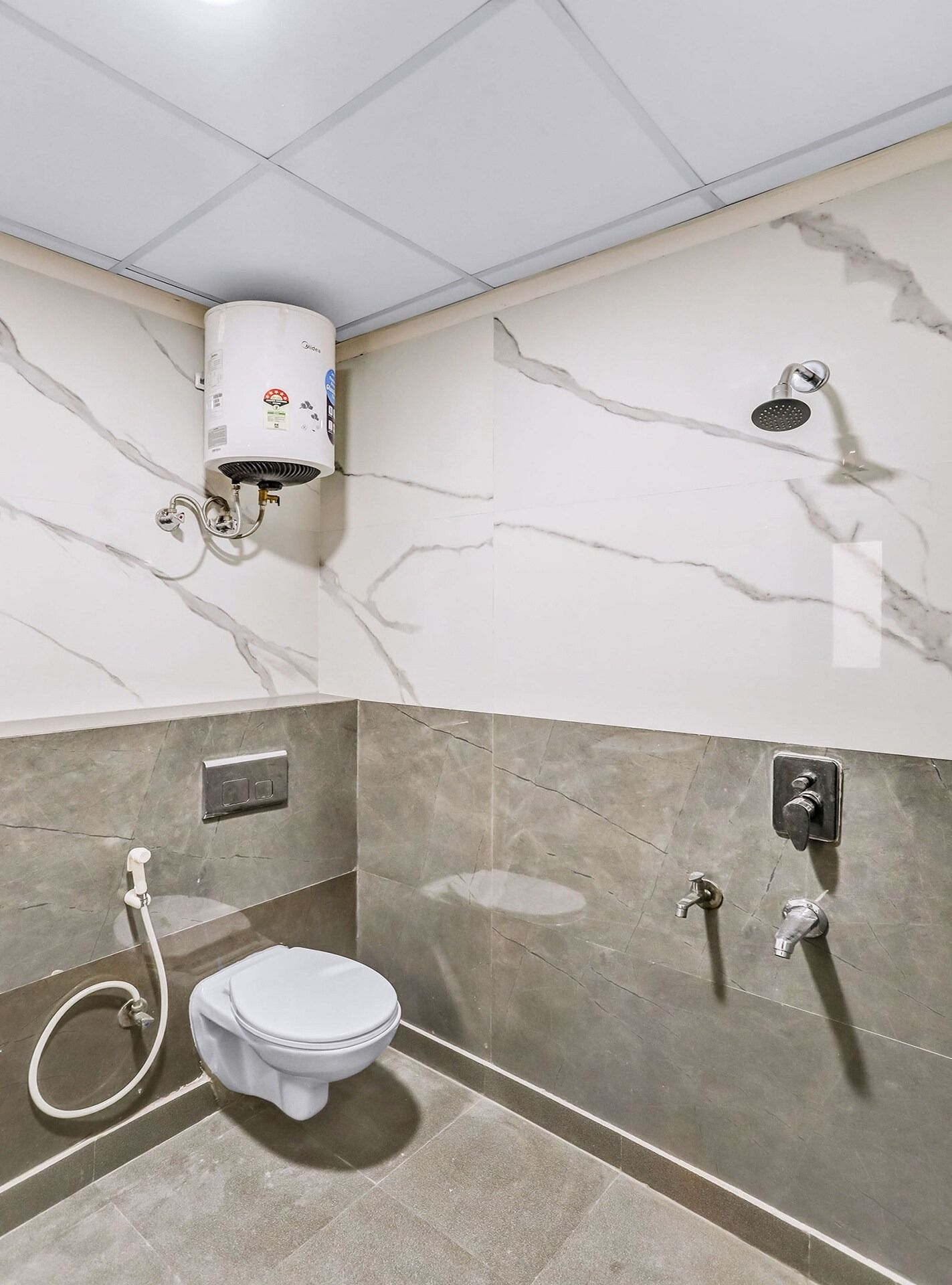 Une salle de bain équipée de toilettes, d’une douche et d’un chauffe-eau.