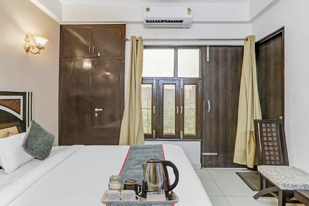 Habitació d'hotel amb un llit, una taula de nit amb un plat de menjar per esmorzar, una finestra amb cortines i un armari.