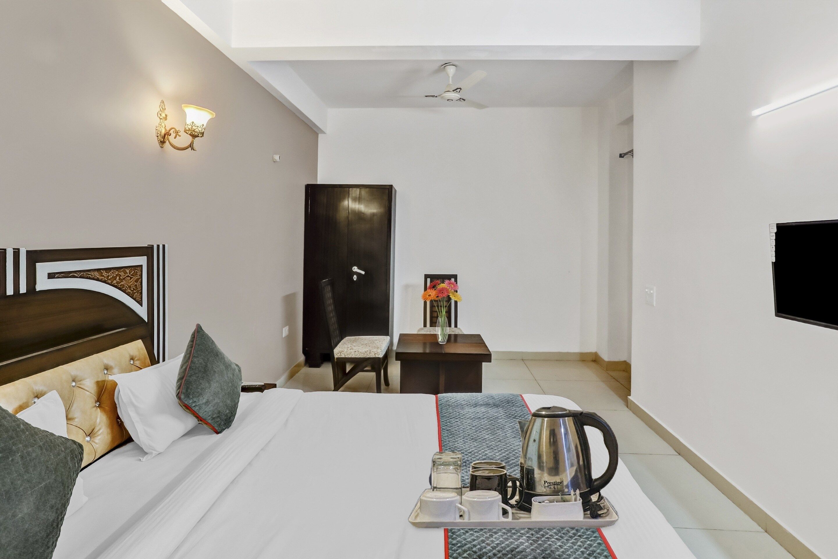 Une chambre d’hôtel équipée d’un lit, d’une table de chevet, d’un bureau, d’une chaise, d’une télévision et d’un ventilateur de plafond.