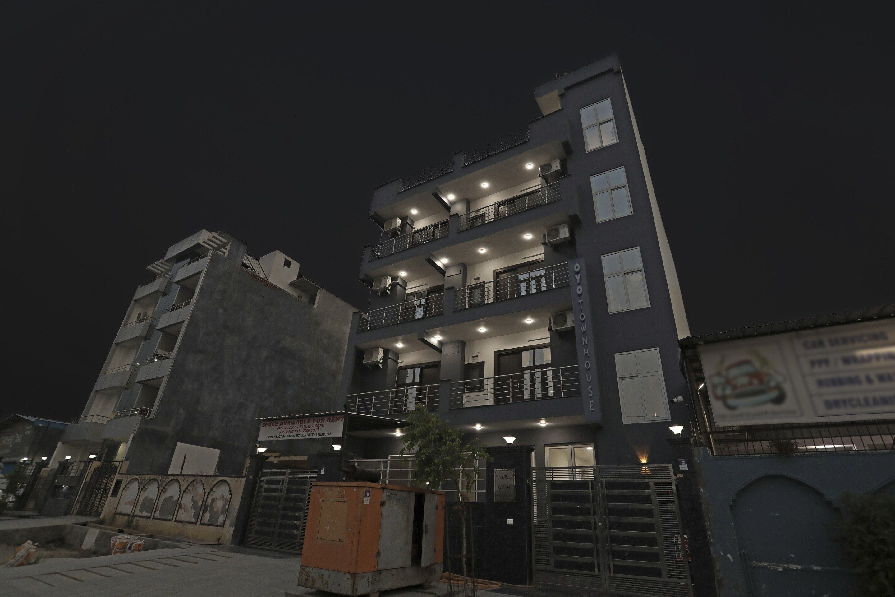 Un edificio de varios pisos con balcones y una entrada protegida por una reja.