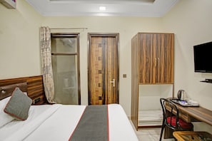 Een hotelkamer met een bed, een bureau, een stoel, een televisietoestel en een kledingkast.