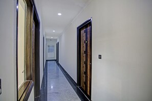 Un pasillo con piso pulido, puertas a ambos lados e iluminación empotrada en el techo.