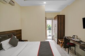 Habitación de hotel con cama, escritorio, silla y vistas al exterior.