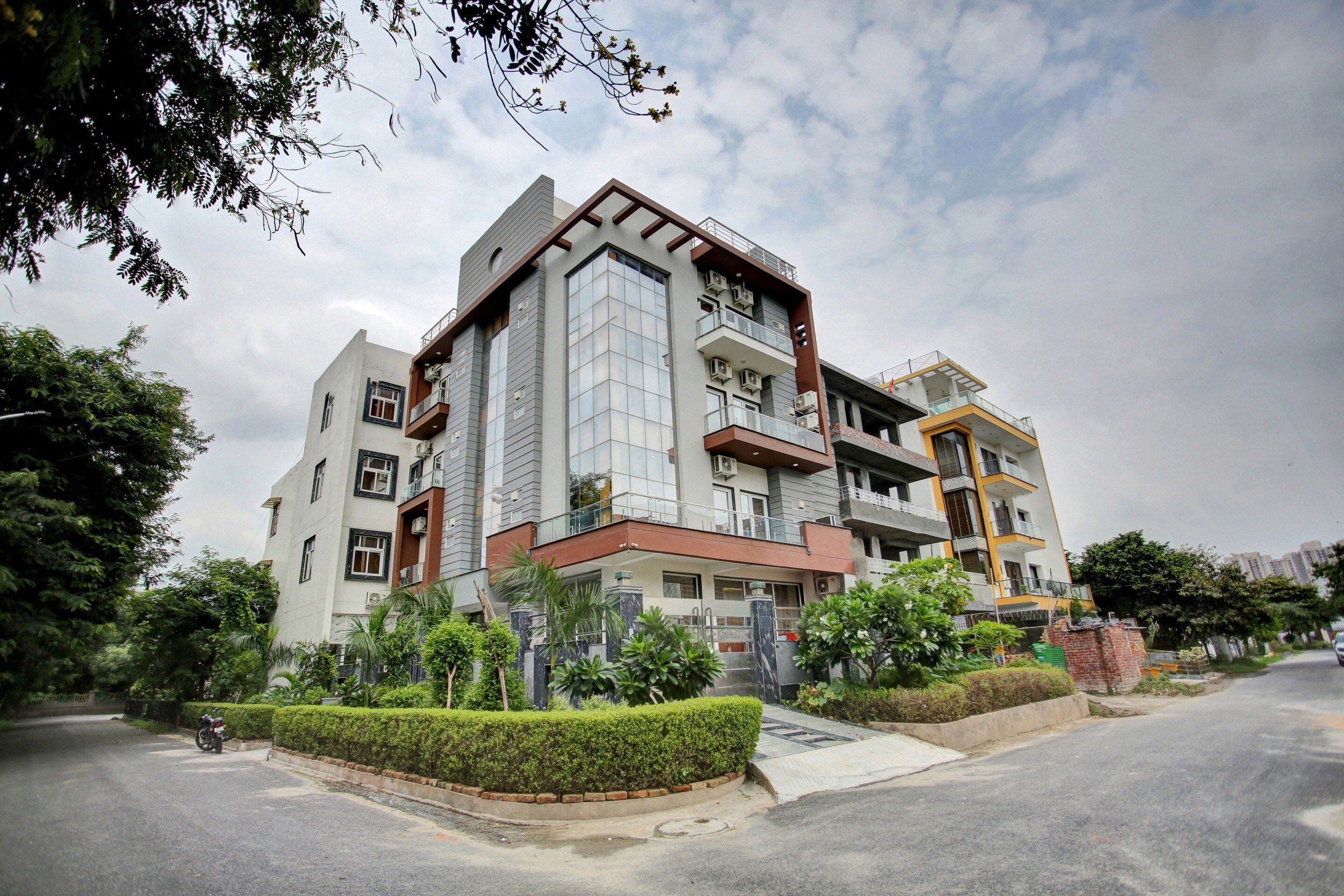 A multi-story residential building with balconies, a gated entrance, and surrounding greenery.