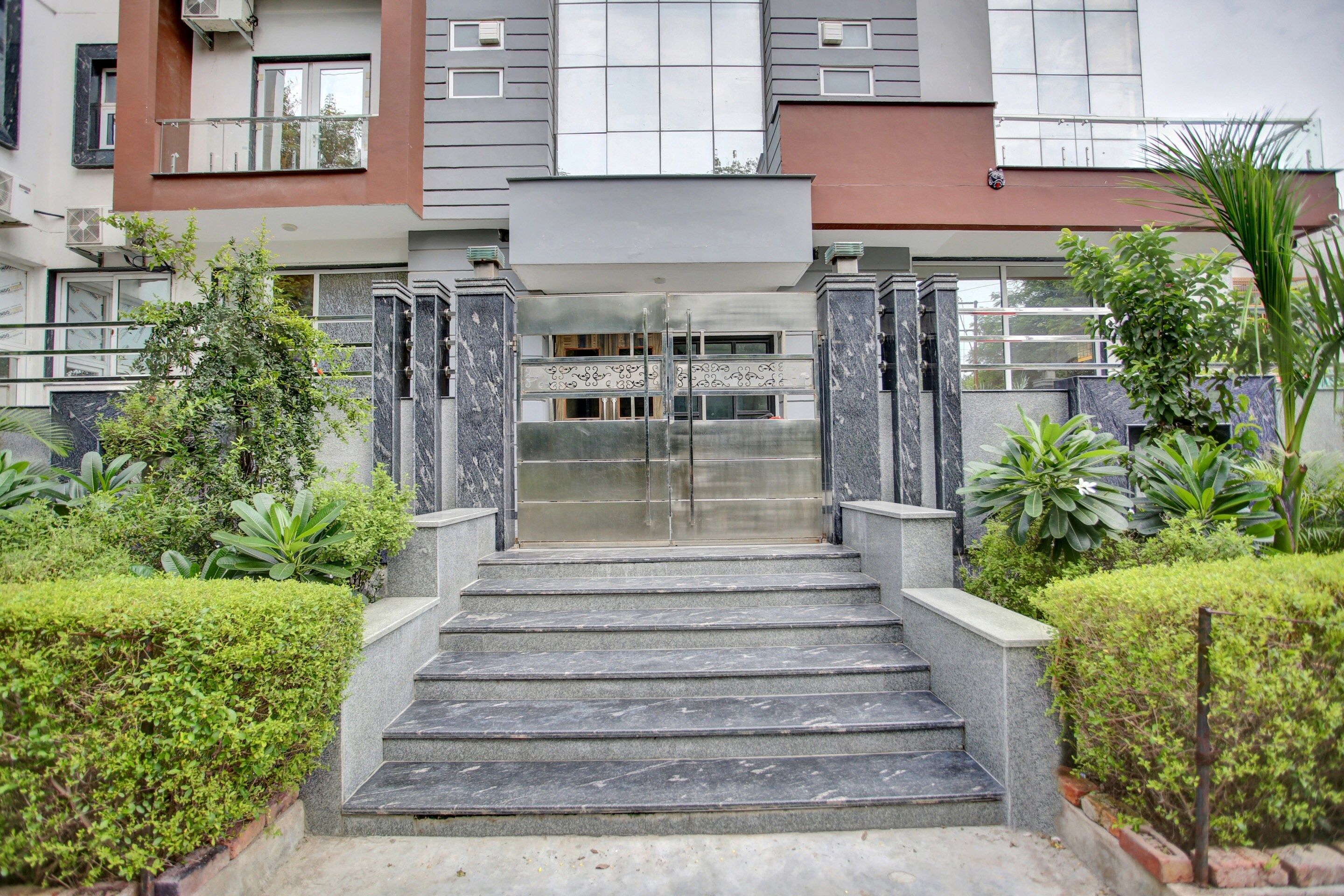 A modern building with a central entrance, surrounded by well-maintained greenery and a clear sky.