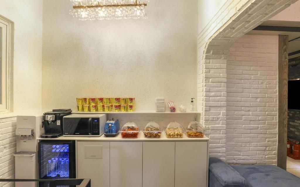 A kitchenette with a microwave, coffee maker, and a refrigerator. There are snack containers on the counter.