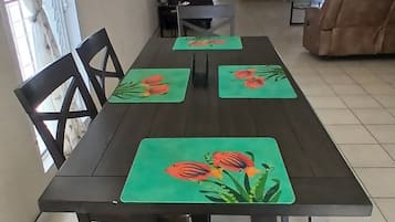 A dining area with a long table, chairs, and green placemats with fish designs.