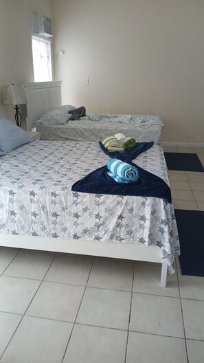 Una cama con una colcha estampada, una toalla enrollada y una almohada.