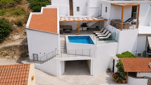 Un edificio moderno a due piani con piscina, posti a sedere all'aperto e un patio coperto.
