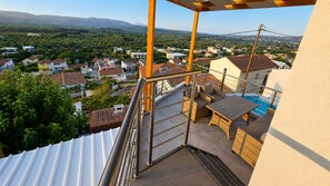 Ein Balkon mit Blick auf eine Wohngegend, ein Schwimmbad und Gartenmöbel.