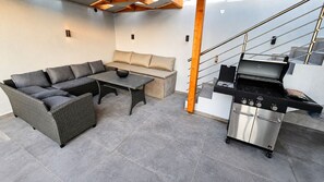 Ein moderner Außenbereich mit einer Couch, einem Tisch und einem Grill.