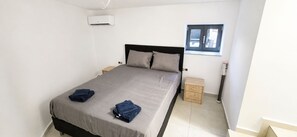 Una camera da letto con un letto, due comodini, una finestra e un condizionatore d'aria.