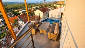 Un balcone con mobili da esterno, una piscina e vista su una zona residenziale.