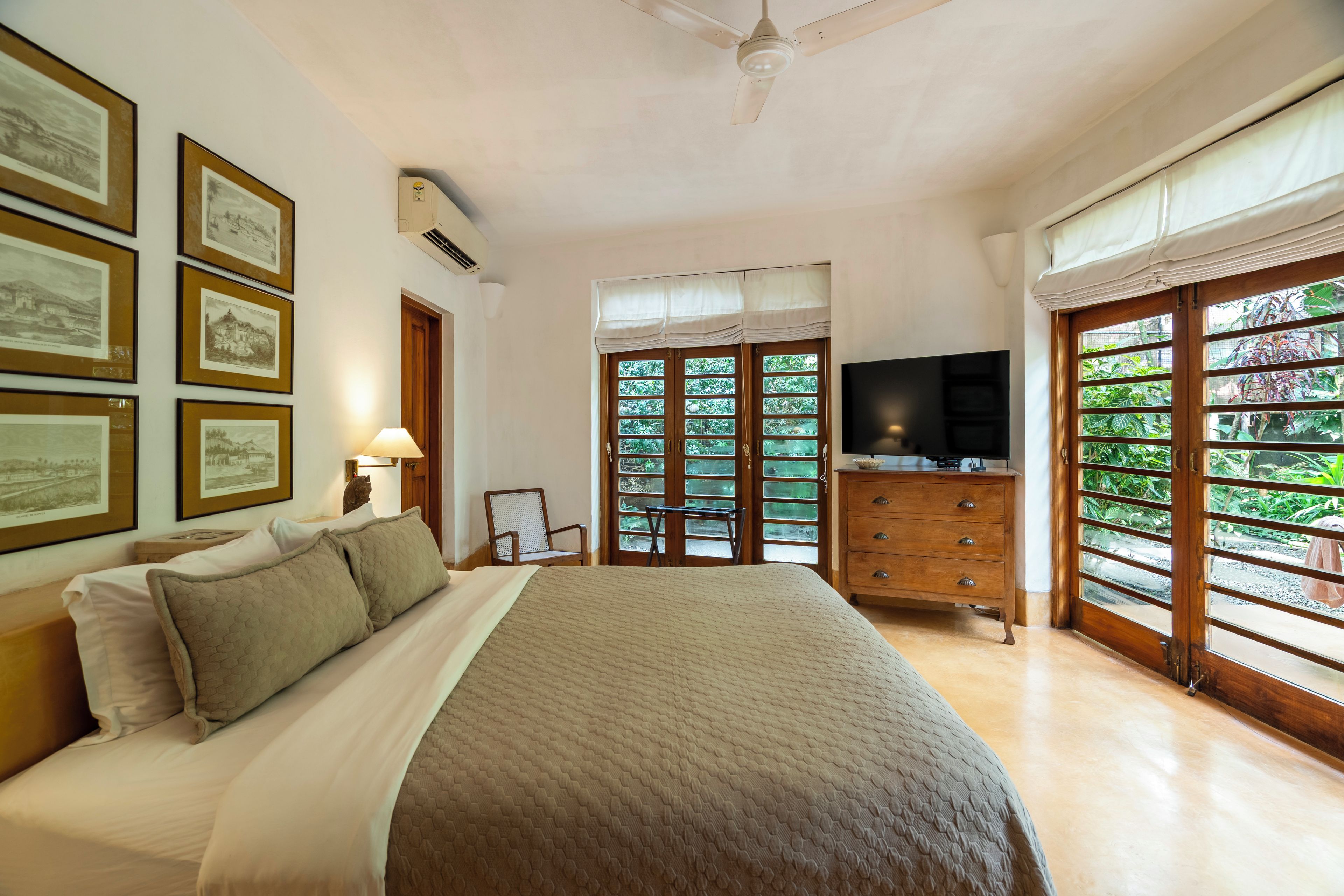 A bedroom with a bed, a dresser, a television, and framed pictures on the wall.