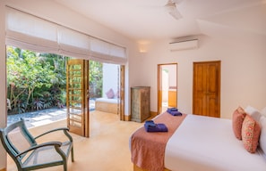 Ein Schlafzimmer mit Bett, einer Bank, einem Kleiderschrank und Blick ins Grüne.