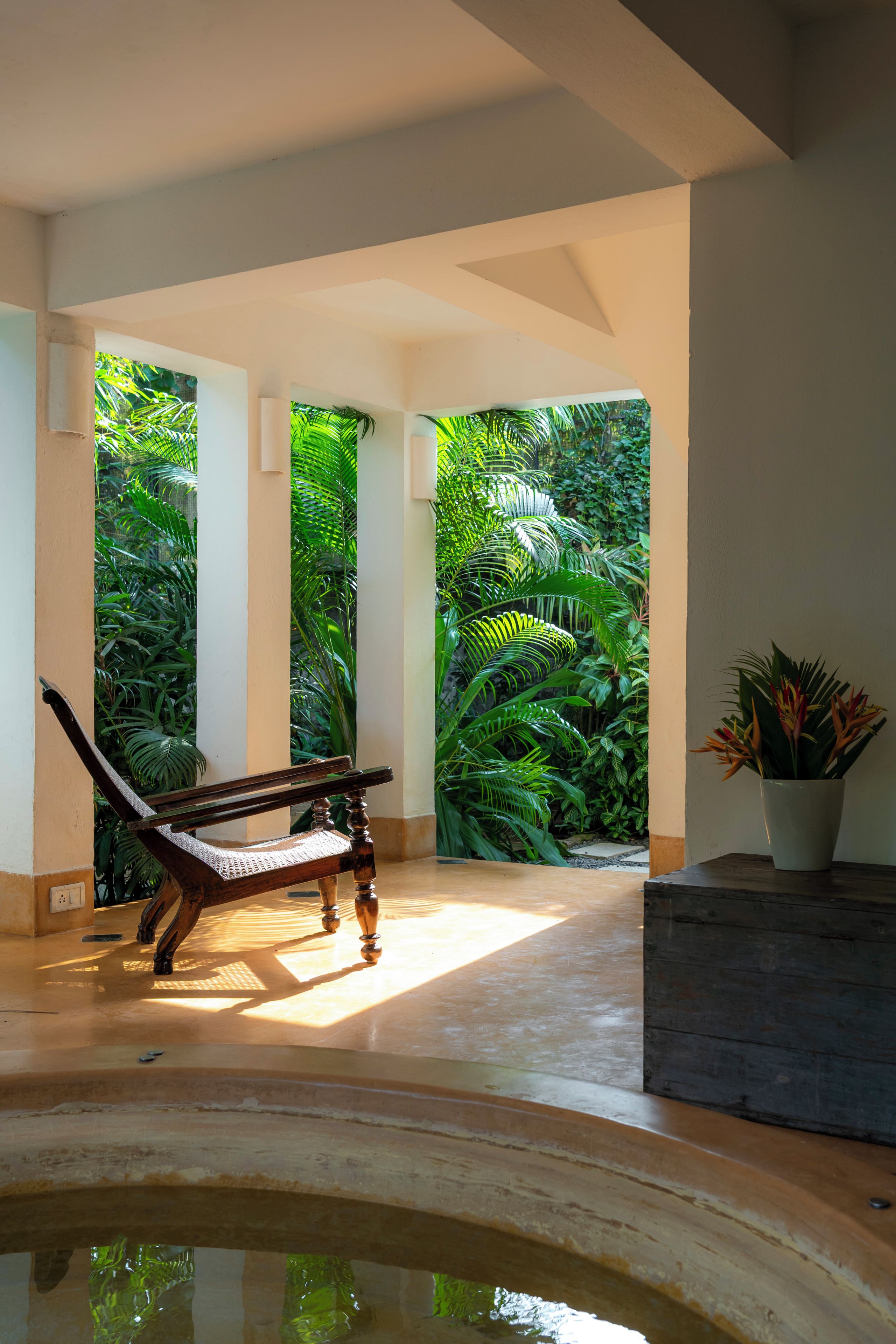 Um banco em um quarto com vista para um verdejante jardim através de uma janela.