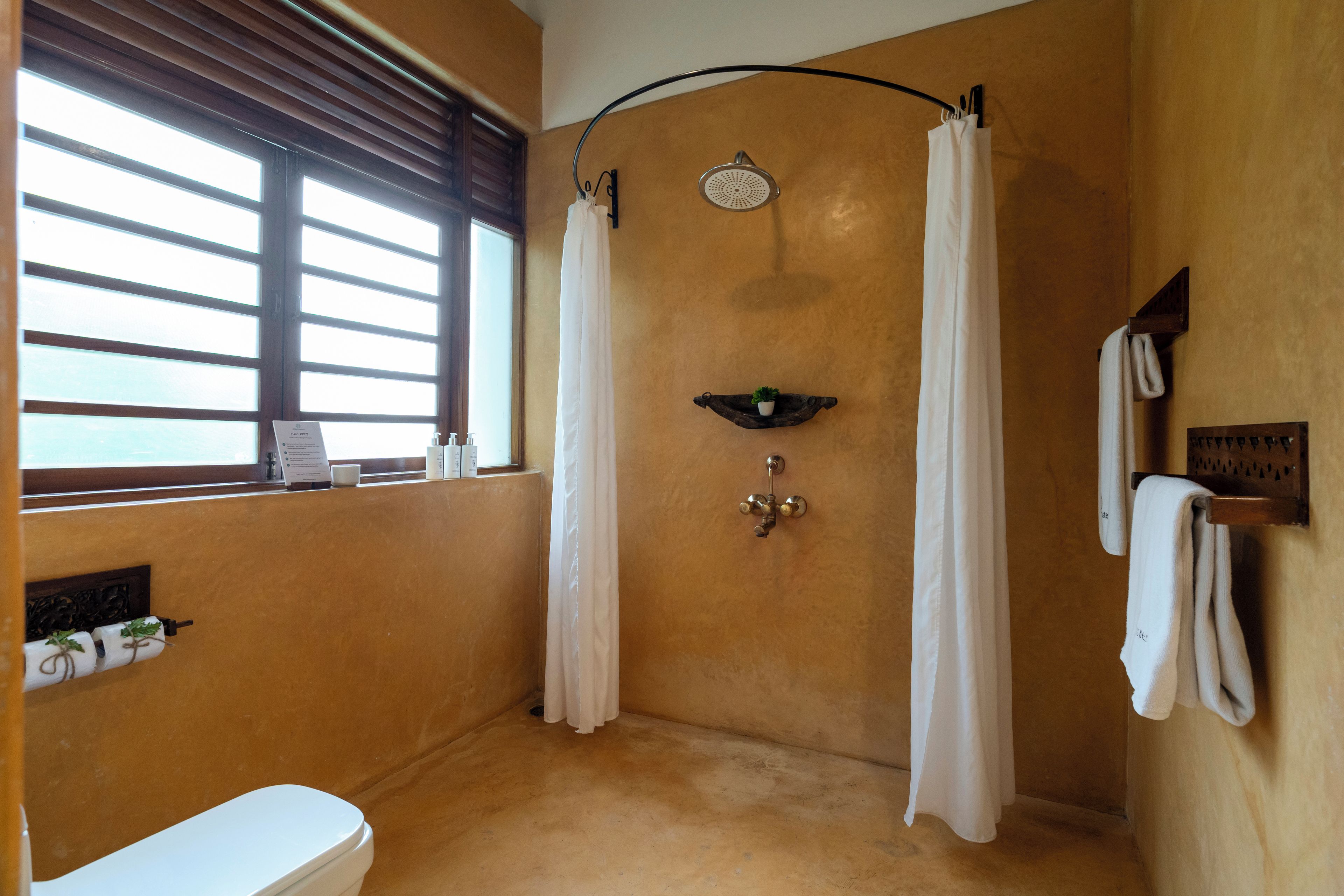 A bathroom with a shower, toilet, and a window.