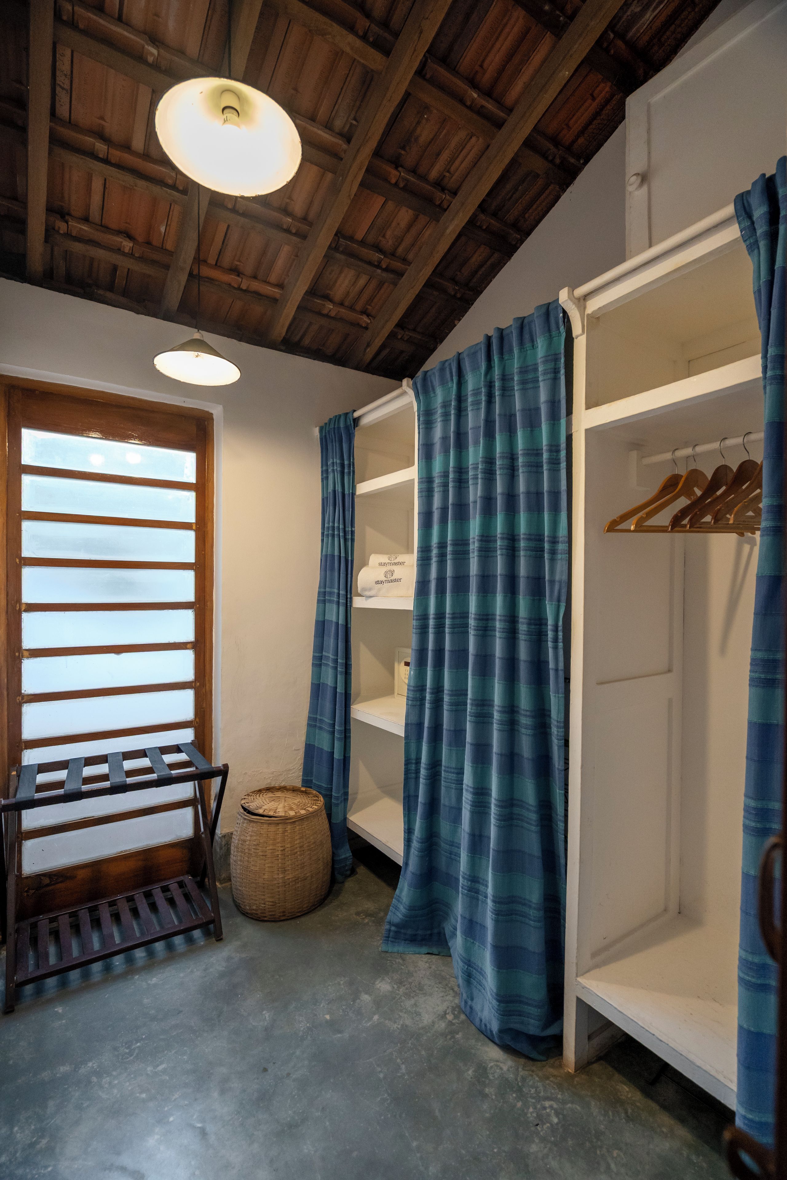 A room with a bunk bed, a wooden bench, a basket, and a hanging light fixture.