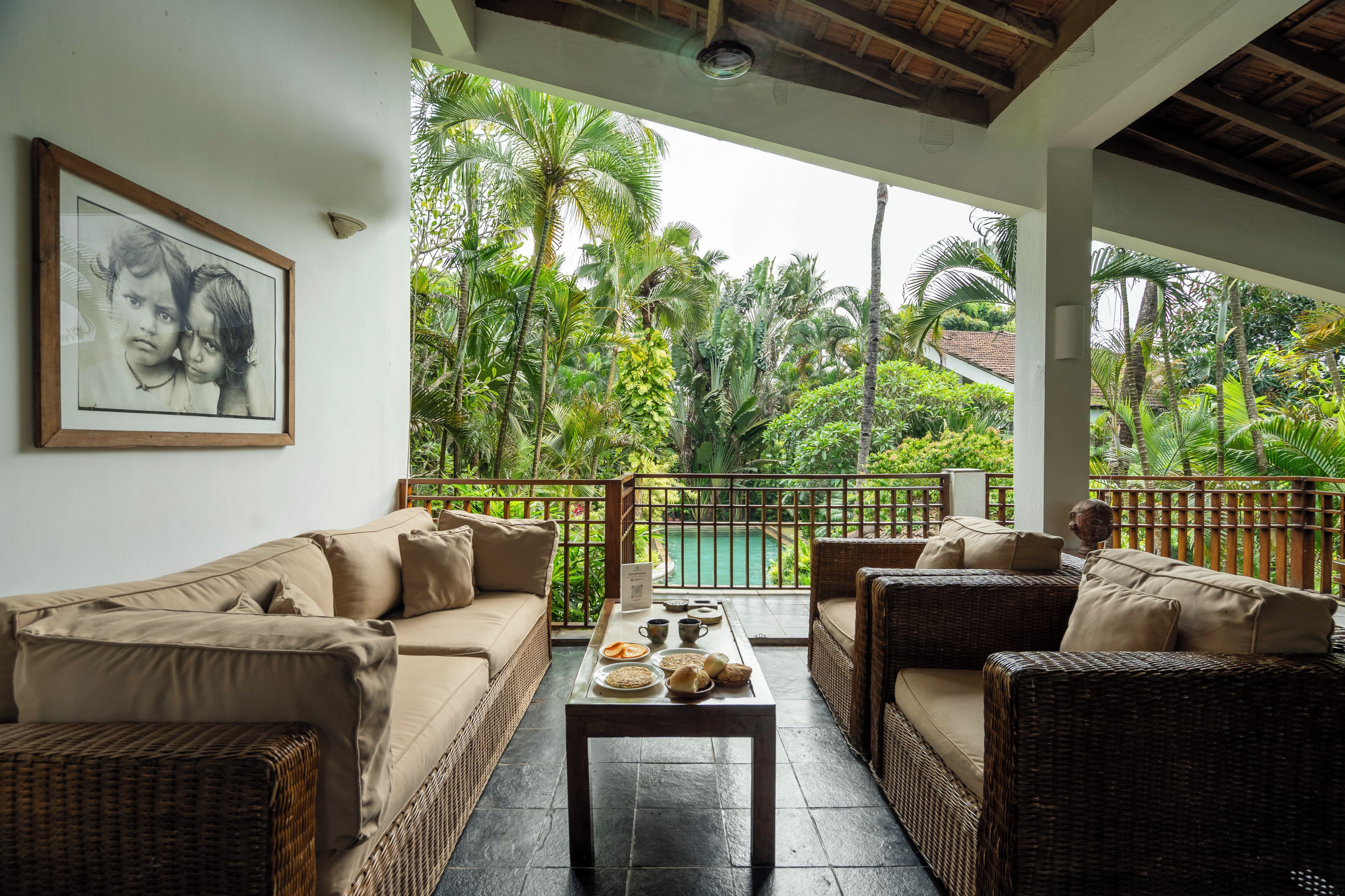 Una habitación con sofá, una mesa de comedor con comida y vistas a una piscina y follaje.