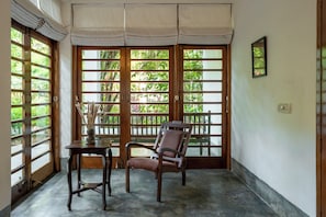 A room with a view through a wooden door with glass panels, a table, and a chair.