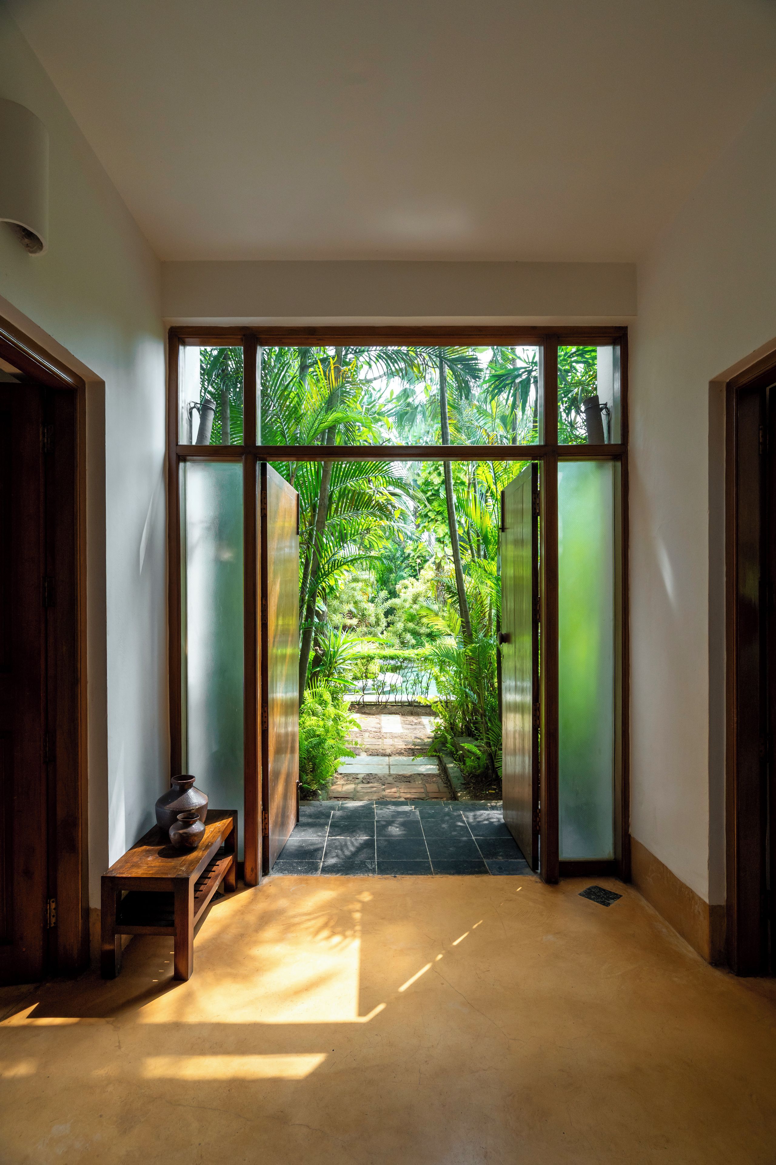 Corredor com vista para um jardim através de uma porta de vidro.