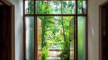 Corredor com vista para um jardim através de uma porta de vidro.
