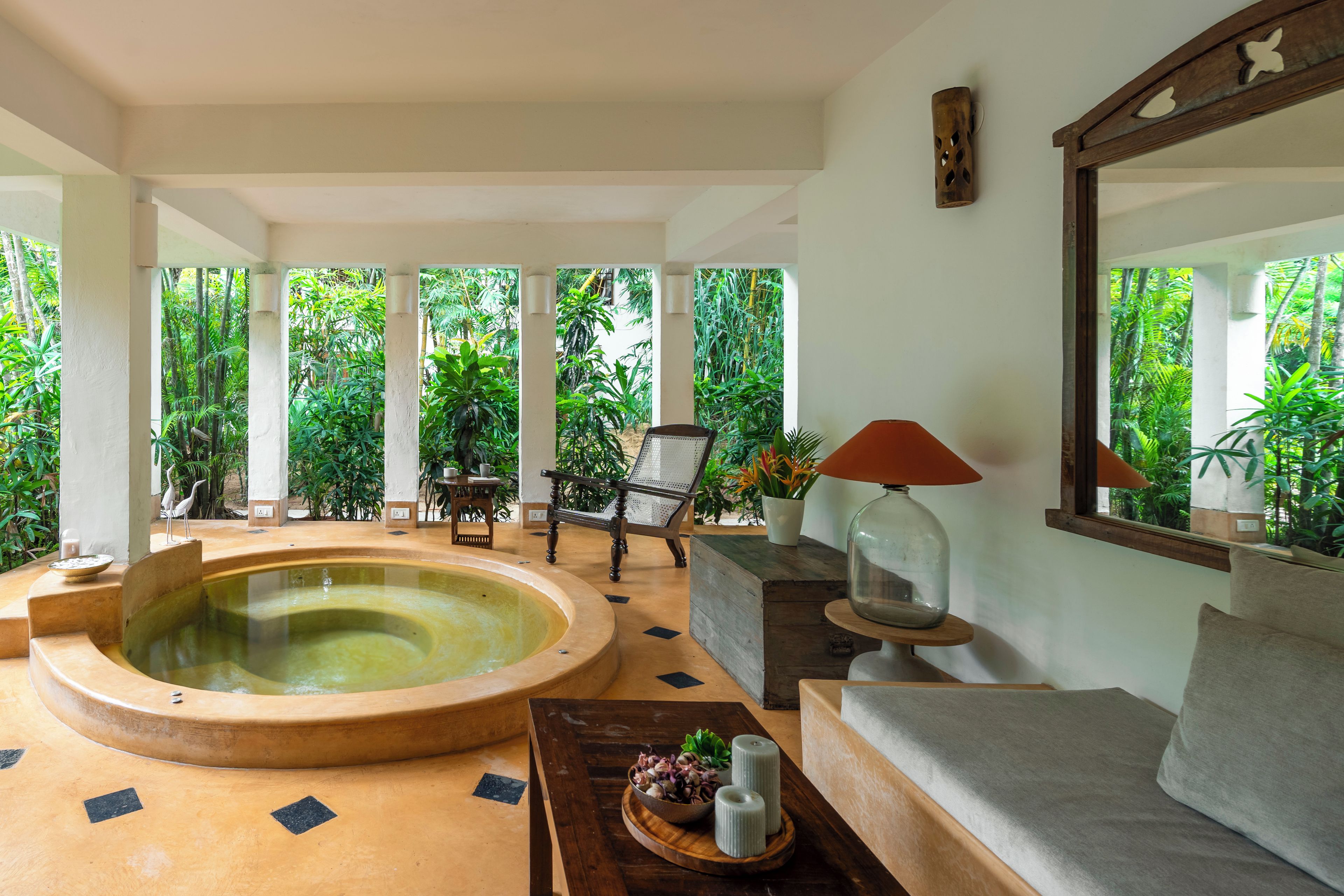 Área de spa com hidromassagem, assentos e vista para vegetação exuberante.