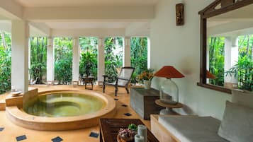 Área de spa com hidromassagem, assentos e vista para vegetação exuberante.