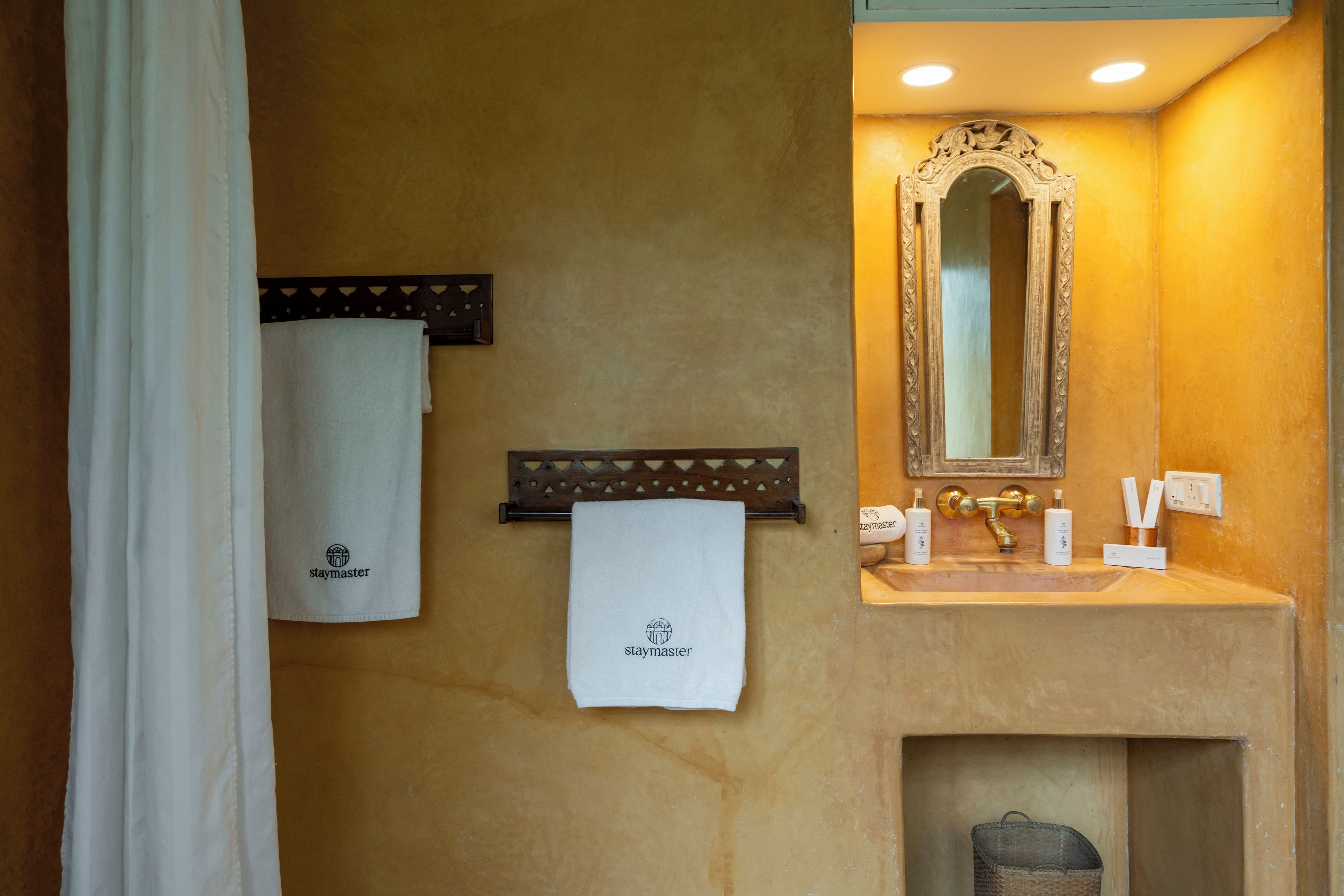 Een badkamer met een handdoekhouder, een spiegel, een wastafel en toiletartikelen.