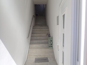 Un escalier avec un paillasson à sa base, menant à une porte dotée d’une fenêtre.