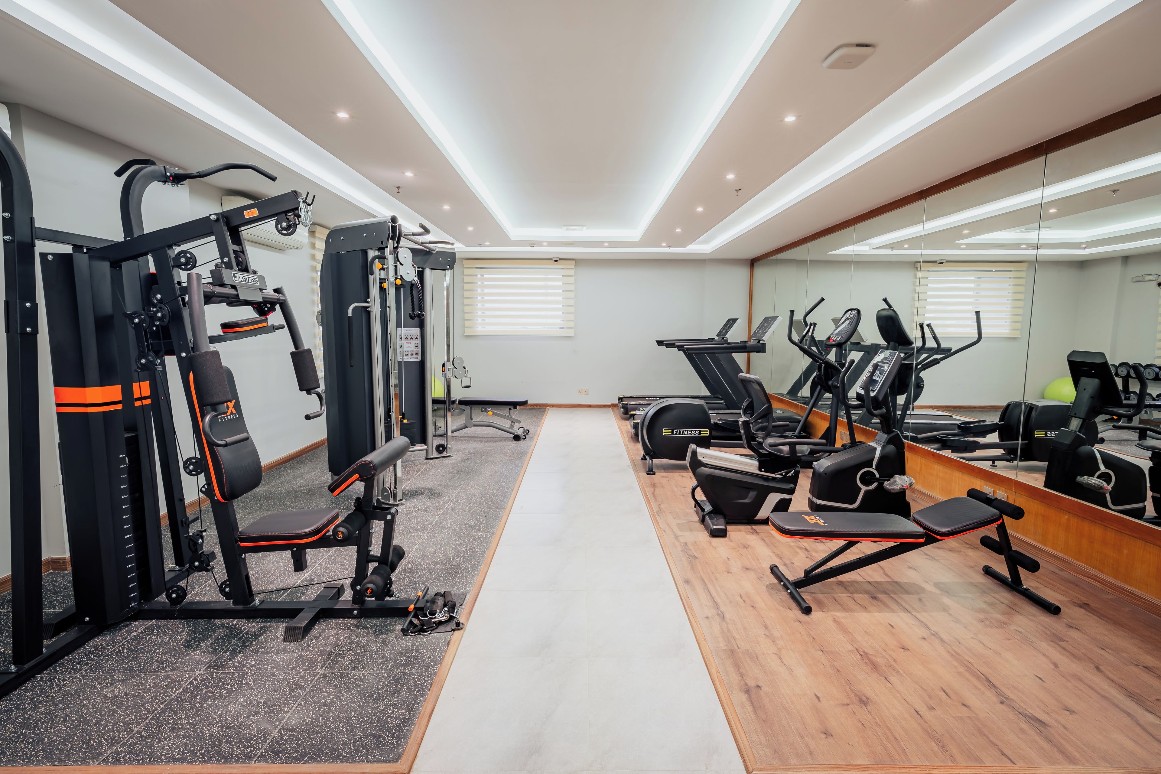 A gym with cardio machines, weightlifting equipment, and a mirrored wall.