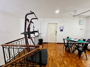 A room with a wooden staircase, a door, a table with chairs, and a ceiling fan.