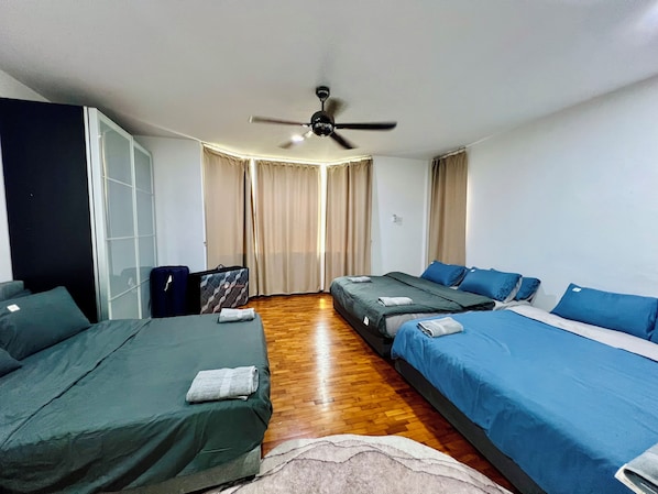 A hotel room with two single beds, a ceiling fan, a wardrobe, and a suitcase.