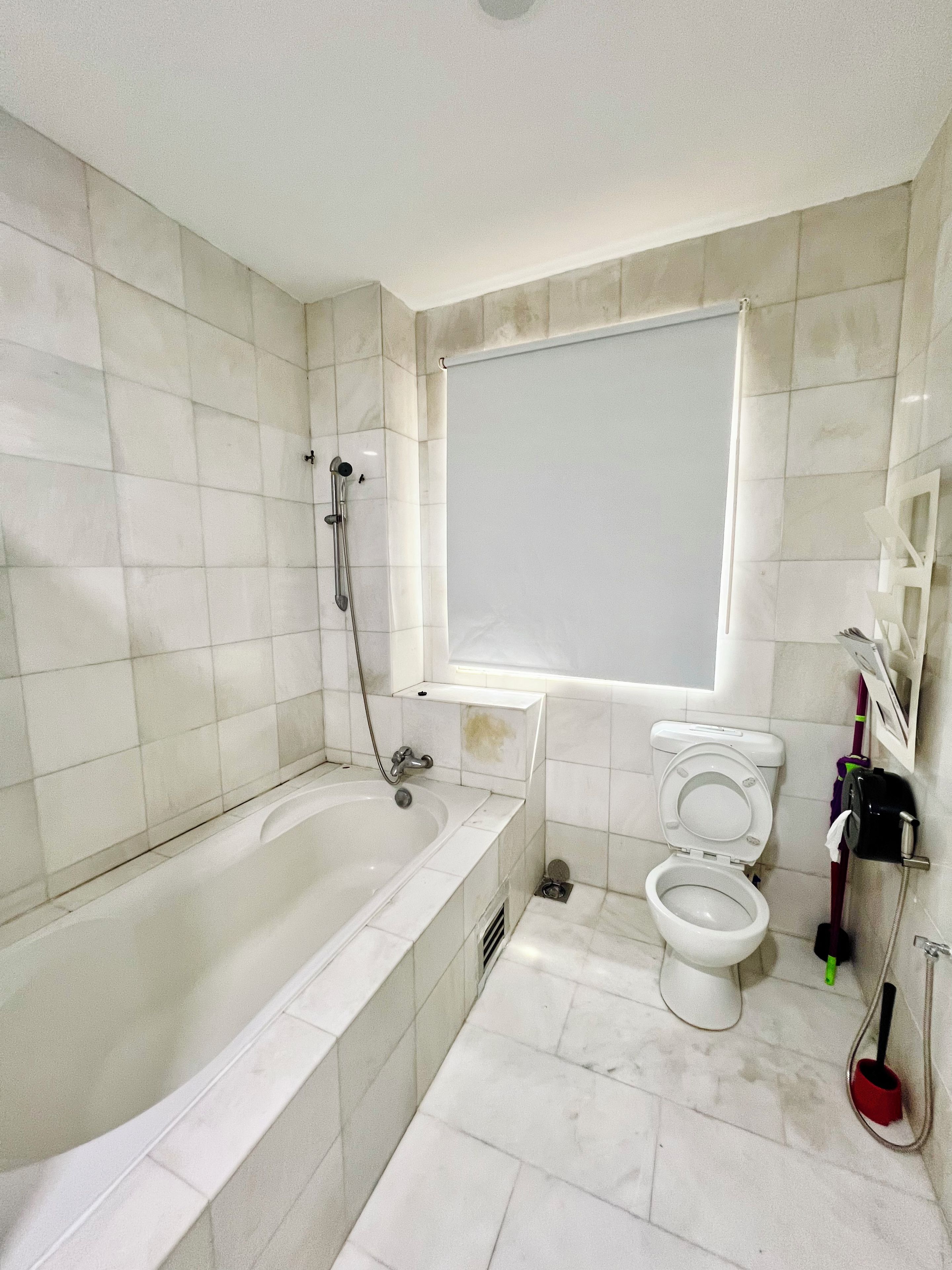 A bathroom with a bathtub, toilet, and a window.