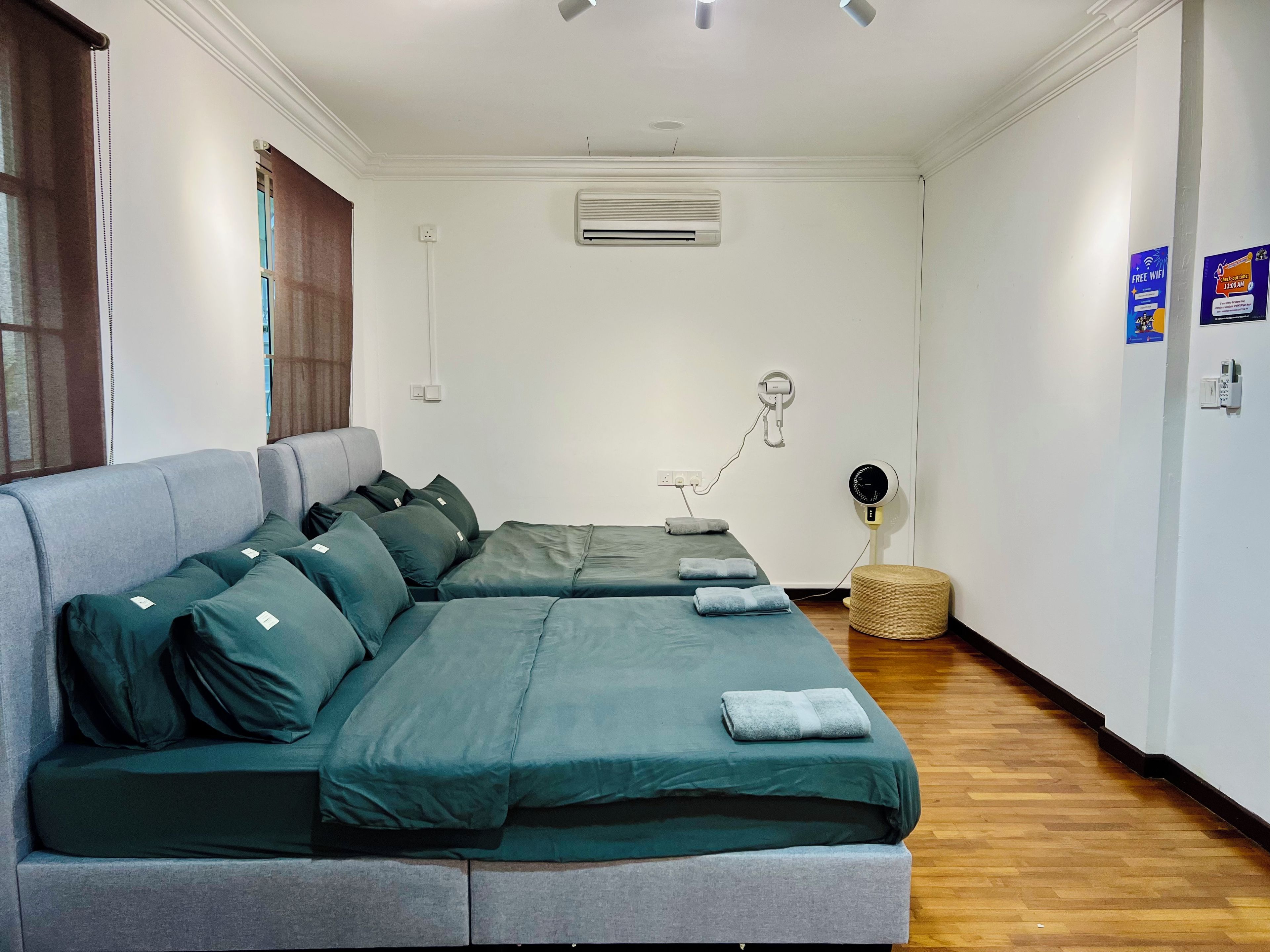 A modern bedroom with a grey sofa bed, a bedside table with a lamp, and a wall-mounted air conditioner.