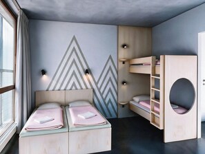 Un dormitori modern amb dos llits, un llit superposat i un disseny de paret geomètric.