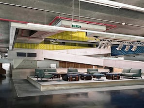 Un espacio interior de varios niveles con zonas de estar, una escalera y una señal de orientación.