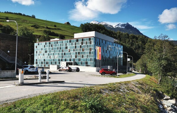 Un edificio moderno con fachada de vidrio, rodeado de un paisaje montañoso.