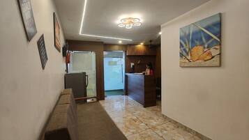 Un pasillo con una mesa de recepción, un banco de madera y un cuadro en la pared.