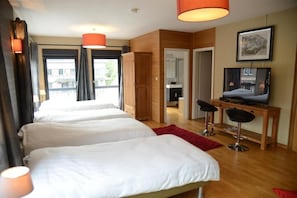 A hotel room with two beds, a desk with a television, and a view of the outside. - Race & Rooms (Stavelot)