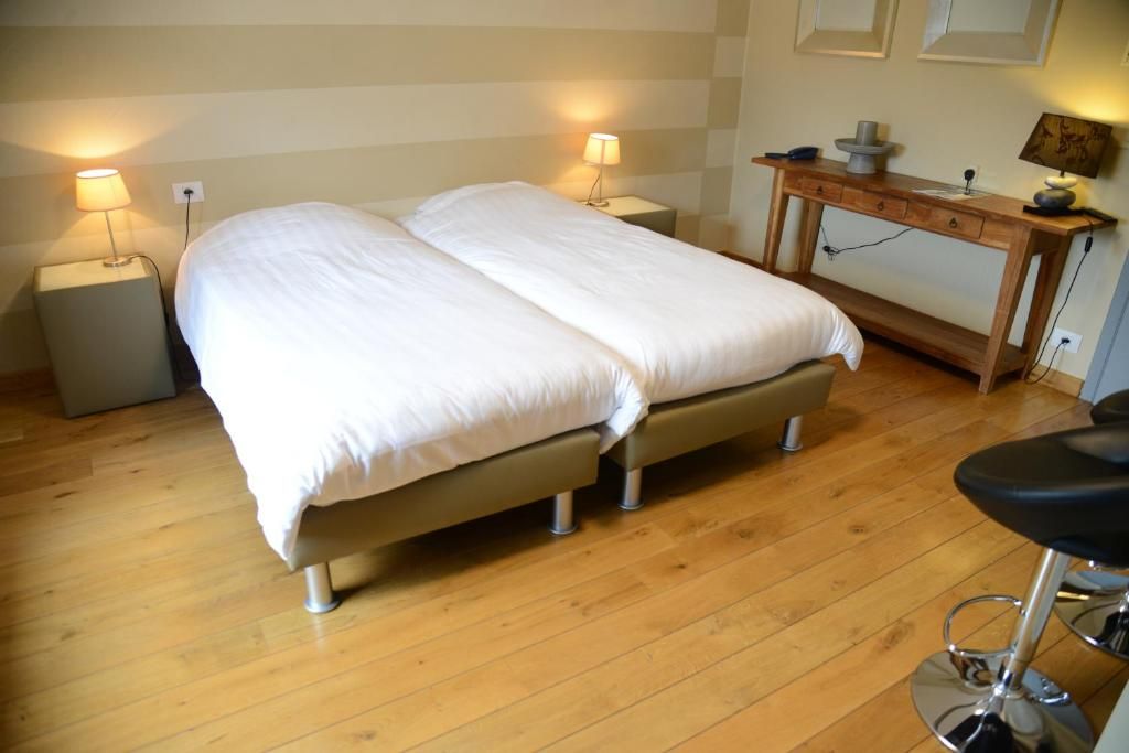 Cama doble con estructura de madera y mesita de noche con lámpara.
