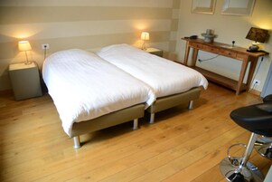Cama doble con estructura de madera y mesita de noche con lámpara.