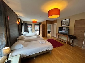 A hotel room with three beds, a TV, a desk, and a red rug. - Race & Rooms (Stavelot)